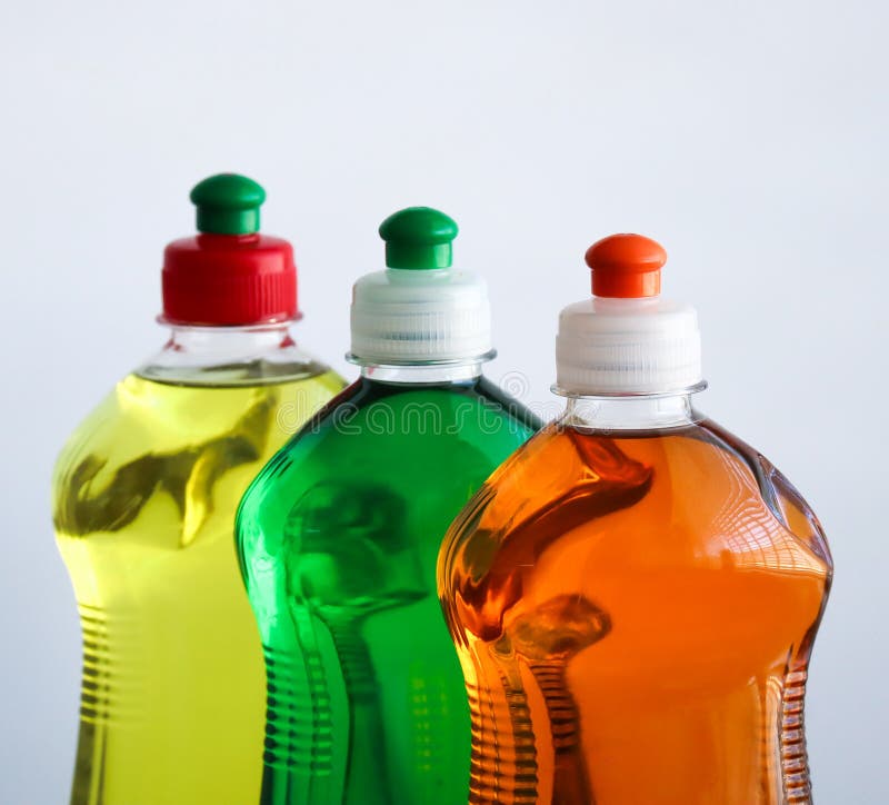 Bottles of Dishwashing Liquid, Glass and Tile Cleaner and Sponges on Green Background Stock