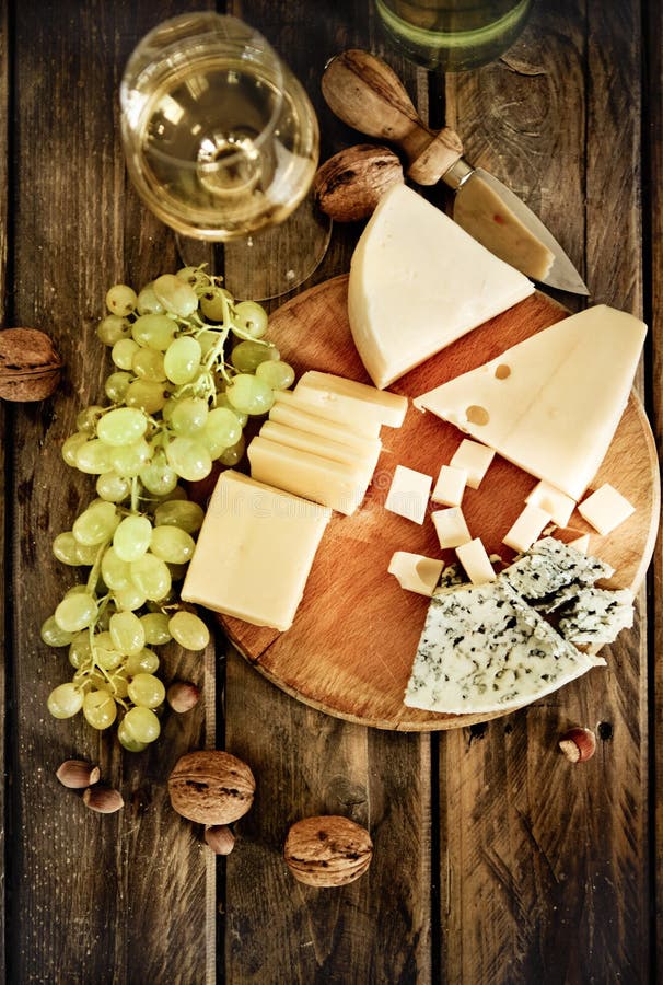 Fľaše a pohár biele víno, syr, orechy a hrozno na drevený.