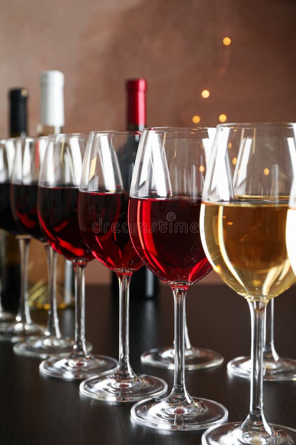 Bottles and glasses with wine on dark table, blurred lights