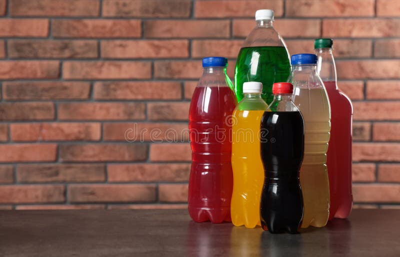 Bottles of Soft Drinks on Table Near Brick Wall. Space for Text Stock