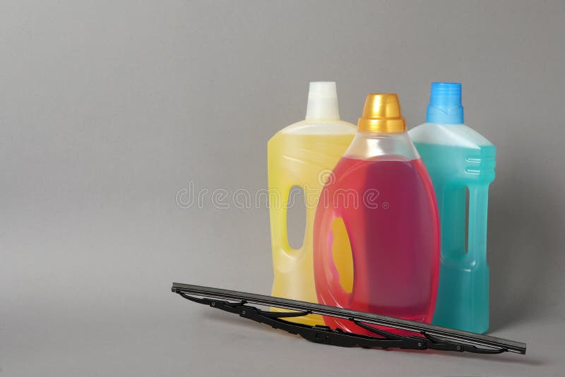 Bottles of Windshield Washer Fluids and Wiper on Grey Background. Space