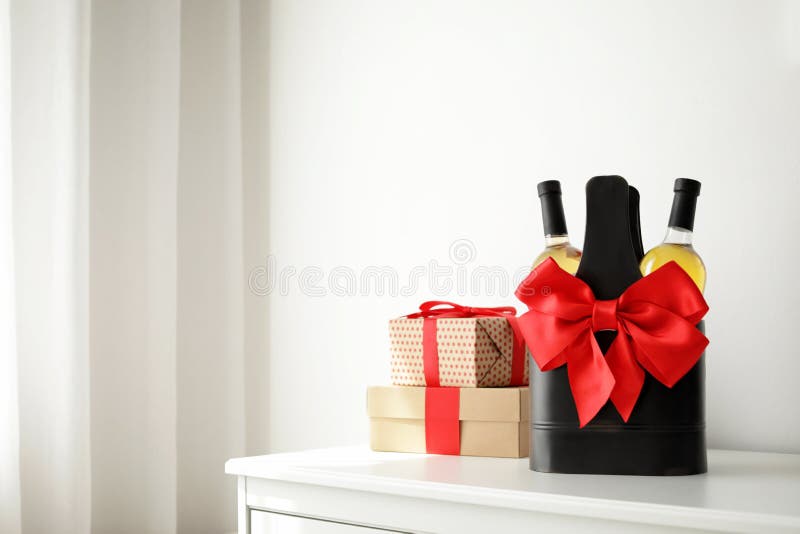 Bottles of Wine in Holder with Bow and Gift Boxes on Table in Light