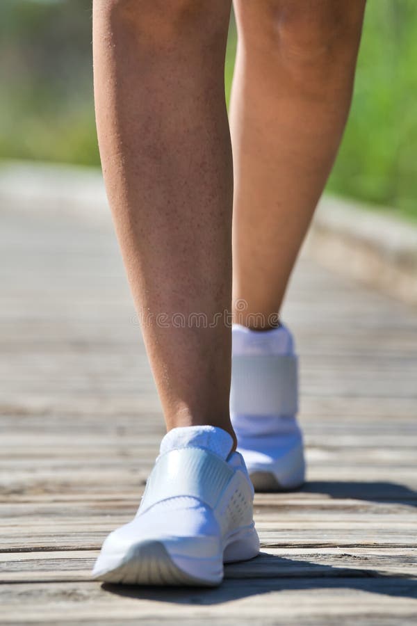 Bottom of running person in which the legs of the person are seen, wearing white shoes with the background out of focus. royalty free stock images