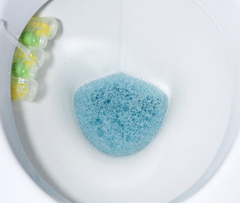Bottom of White Toilet Bowl with Blue Water and Solid Disinfectants