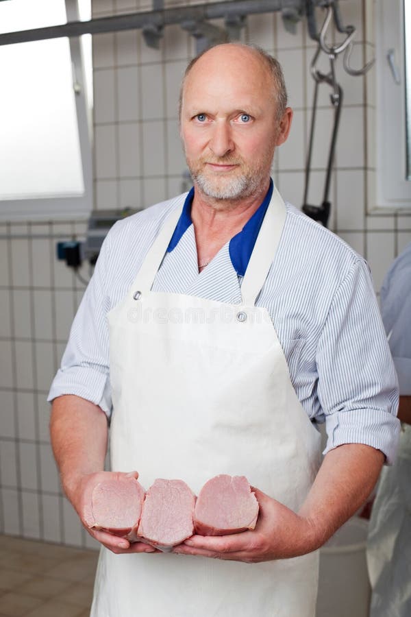 Boucher posant avec des morceaux de viande photos stock Boucher posant avec des morceaux de viande photos stock