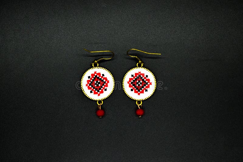 Boucles d'oreille faites main avec le modèle traditionnel roumain rouge et noir D'isolement sur le noir photo stock Boucles d'oreille faites main avec le modèle traditionnel roumain rouge et noir D'isolement sur le noir photo stock