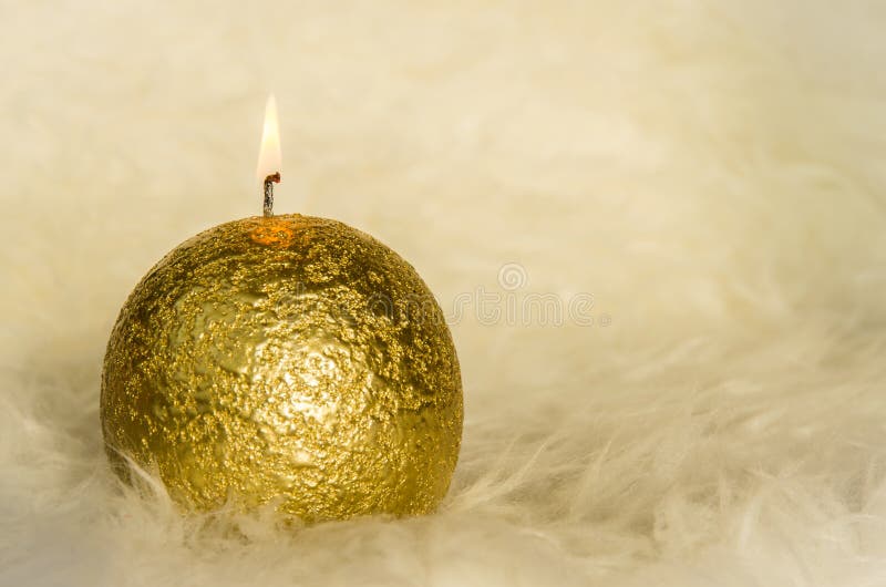 Bougie d'or brûlant sur le fond blanc de fourrure photographie stock libre de droits Bougie d'or brûlant sur le fond blanc de fourrure photographie stock libre de droits