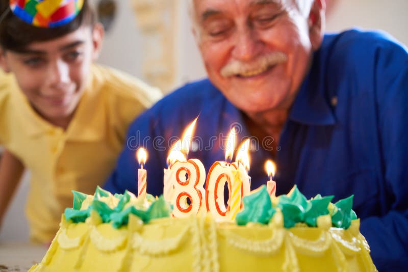 Bougies de soufflement de garçon et d'homme supérieur sur la fête d'anniversaire de gâteau images libres de droits Bougies de soufflement de garçon et d'homme supérieur sur la fête d'anniversaire de gâteau images libres de droits