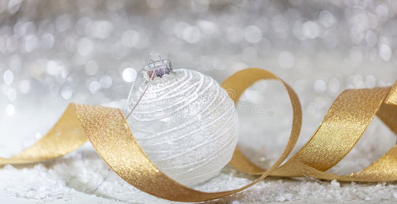 Boule blanche de Noël, ruban d'or et neige, fond abstrait de lumières de bokeh