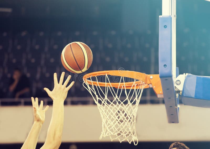 Ball in hoop at basketball game. Basketball players hands. Ball in hoop at basketball game. Basketball players hands