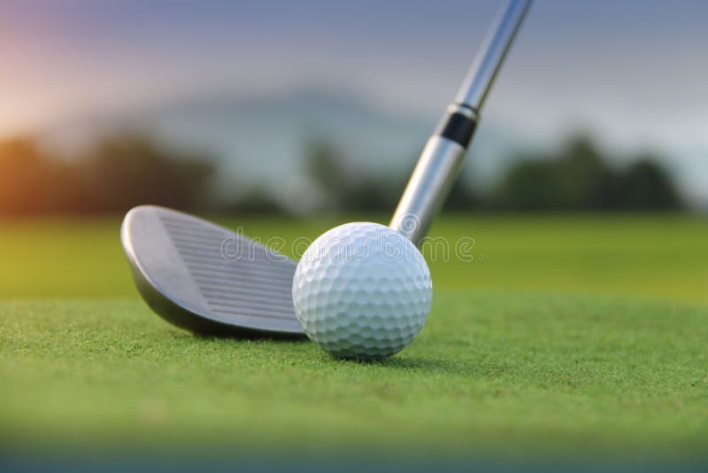 Boule de golf et club de golf dans le beau terrain de golf au fond de coucher du soleil Boule de golf sur le vert dans le terrain photographie stock Boule de golf et club de golf dans le beau terrain de golf au fond de coucher du soleil Boule de golf sur le vert dans le terrain photographie stock