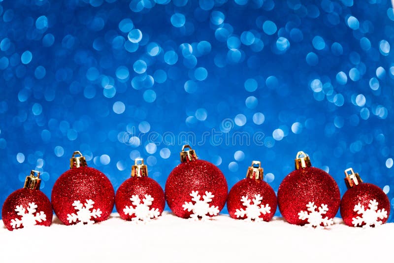 Boules rouges de Noël dans la neige sur le scintillement bleu image libre de droits Boules rouges de Noël dans la neige sur le scintillement bleu image libre de droits