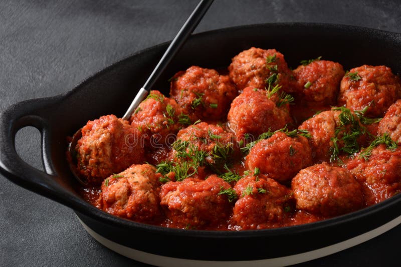 Boulettes de poisson boulettes de poisson frites à la sauce tomate dans un plat blanc. Boulettes de poisson boulettes de poisson frites à la sauce tomate dans un plat noir sur une table en béton avec des ingrédients