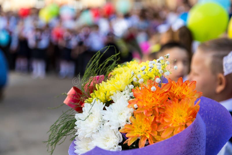 A Bouquet of Flowers in the Hands of Elementary School Students. a Ceremony in the School Yard