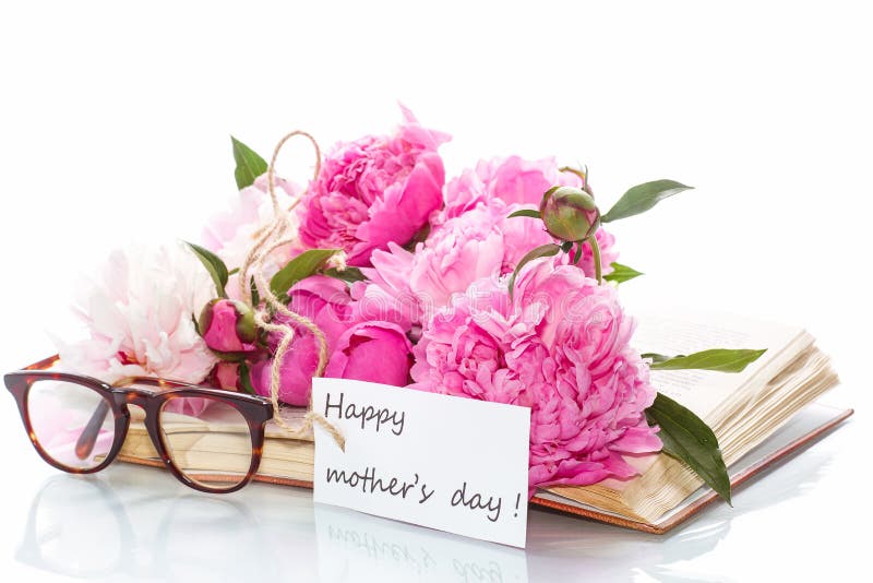 Bouquet of peonies on old book with glasses