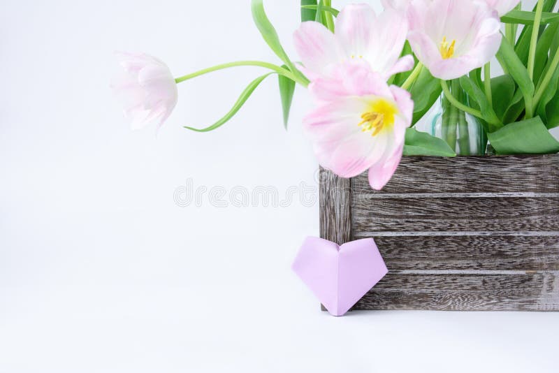 A bouquet of pink tulips in a wooden box and a plum paper heart on a white background. royalty free stock image A bouquet of pink tulips in a wooden box and a plum paper heart on a white background. royalty free stock image
