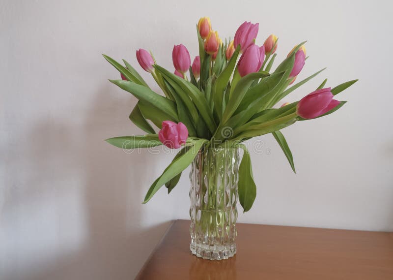 bouquet of pink and yellow tulips in vase closeup across white all on the wooden drawer. Interior detail. Hotel interior .