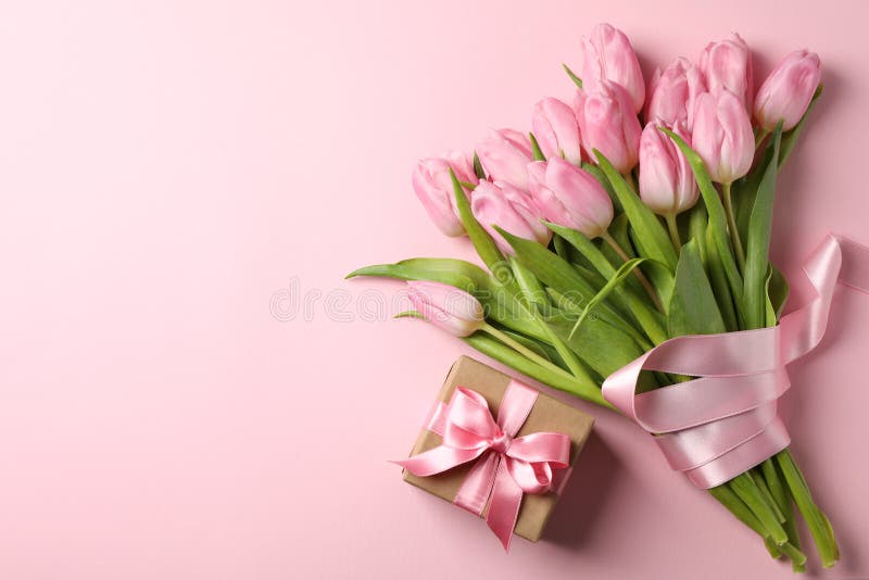 Bouquet of tulips and gift box on background, space for text