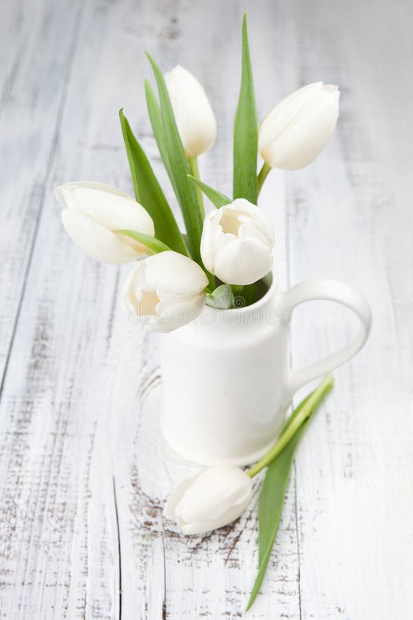 Bouquet of white tulips over white wooden table
