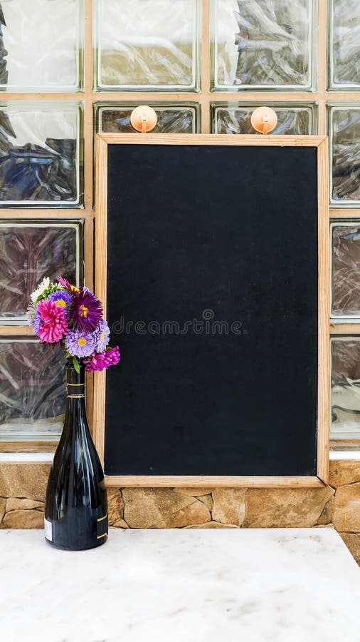 Bouteille avec des fleurs sur un fond d'ardoise photographie stock libre de droits Bouteille avec des fleurs sur un fond d'ardoise photographie stock libre de droits