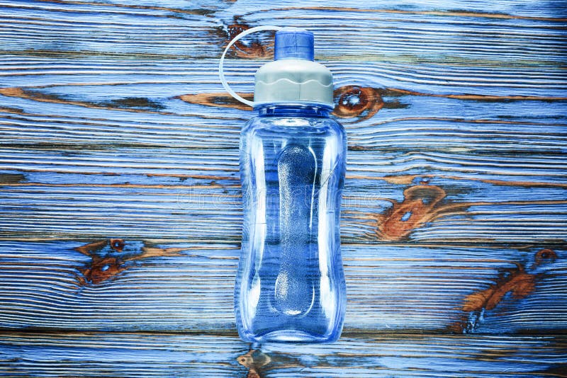 Bouteille d'eau en plastique de forme physique sur le panneau en bois de vintage bleu images libres de droits Bouteille d'eau en plastique de forme physique sur le panneau en bois de vintage bleu images libres de droits