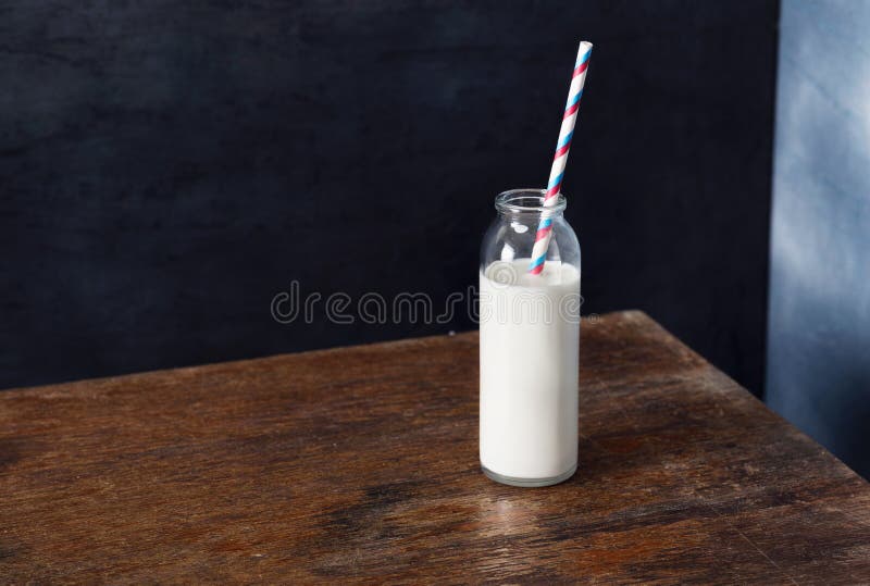 Bouteille en verre de lait avec la paille sur la table en bois image stock Bouteille en verre de lait avec la paille sur la table en bois image stock