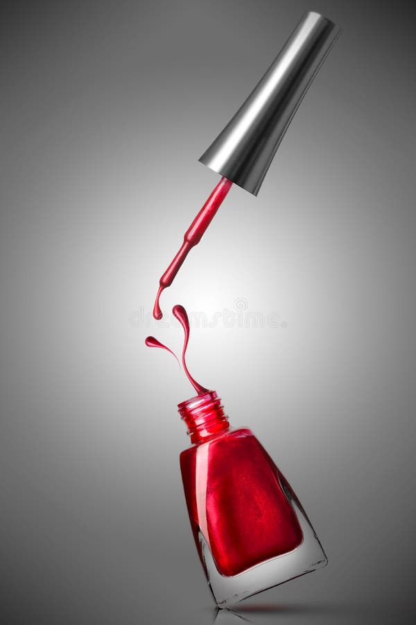 Photo of red nail polish bottle with splash and drops. Photo of red nail polish bottle with splash and drops