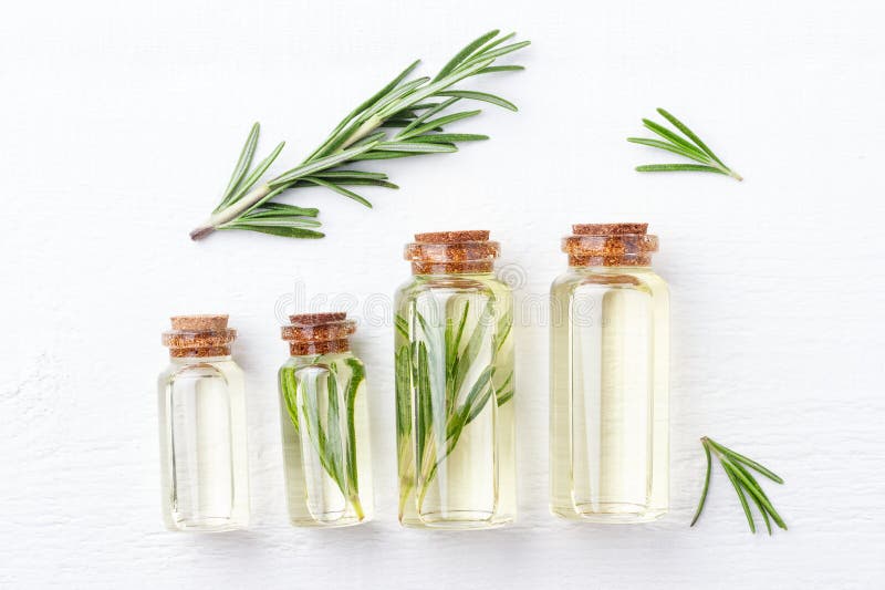 Bouteilles avec de l'huile aromatique du romarin sur le fond en bois blanc image libre de droits Bouteilles avec de l'huile aromatique du romarin sur le fond en bois blanc image libre de droits