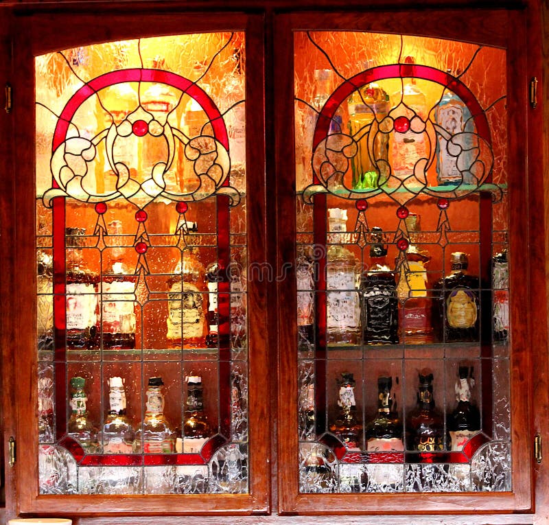 Bouteilles de boisson alcoolisée brouillées derrière l'armoire en verre souillée images stock Bouteilles de boisson alcoolisée brouillées derrière l'armoire en verre souillée images stock