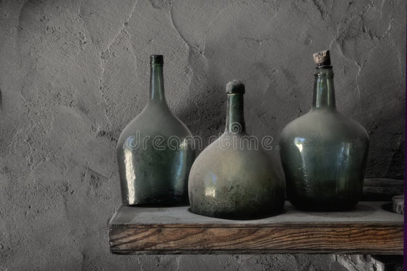 Three old dusty wine bottles in a cellar with stucco walls. Three old dusty wine bottles in a cellar with stucco walls.