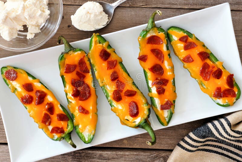 Boutons-pression de Jalapeno avec du fromage et des pepperoni d'un plat blanc photos libres de droits Boutons-pression de Jalapeno avec du fromage et des pepperoni d'un plat blanc photos libres de droits