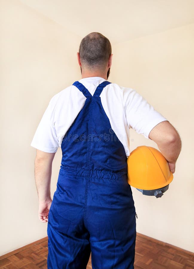 Bouwarbeider en handbediende op de bouwplaats met beschermende uniform, beklede en gele helmhouderij stock fotografie Bouwarbeider en handbediende op de bouwplaats met beschermende uniform, beklede en gele helmhouderij stock fotografie