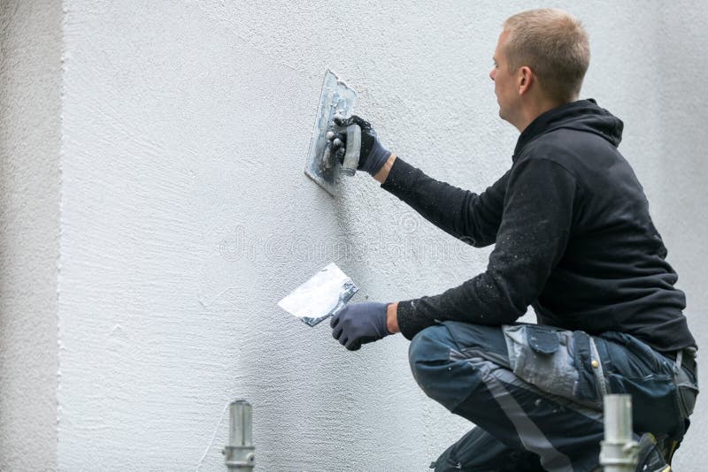 Bouwvakker die decoratief pleister op huisbuitenkant zetten stock afbeelding Bouwvakker die decoratief pleister op huisbuitenkant zetten stock afbeelding