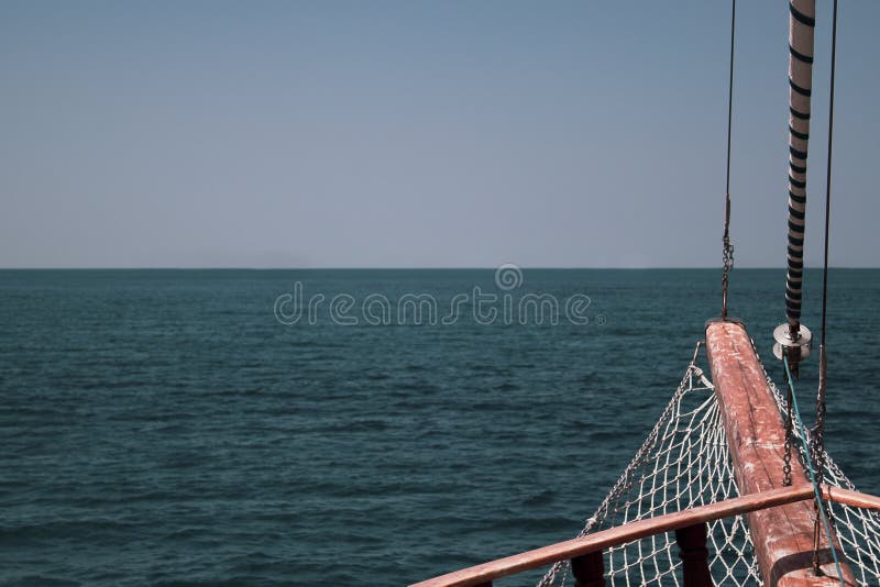 The bow of the ship against the sea horizon with a grid, steel cables and a folded sail. stock photo The bow of the ship against the sea horizon with a grid, steel cables and a folded sail. stock photo