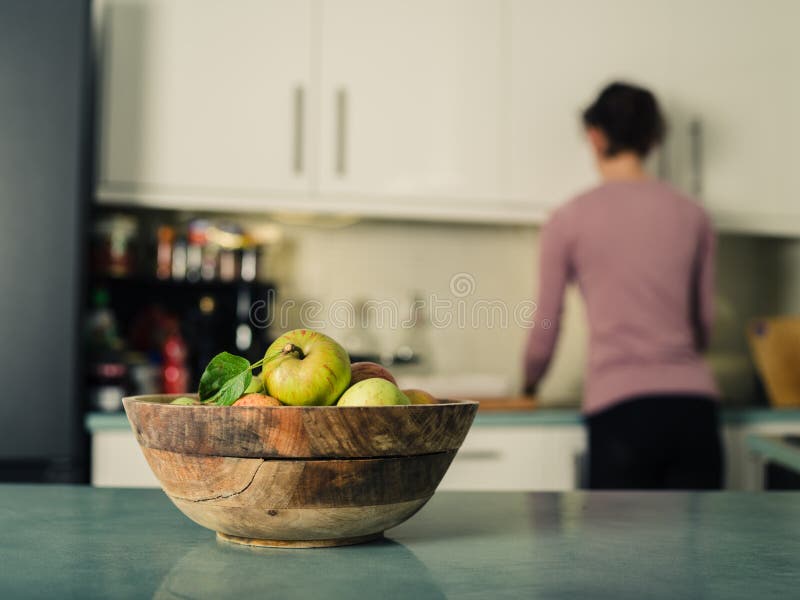 Bowl Of Apples In Kitchen With Woman In Background Stock Photo Image