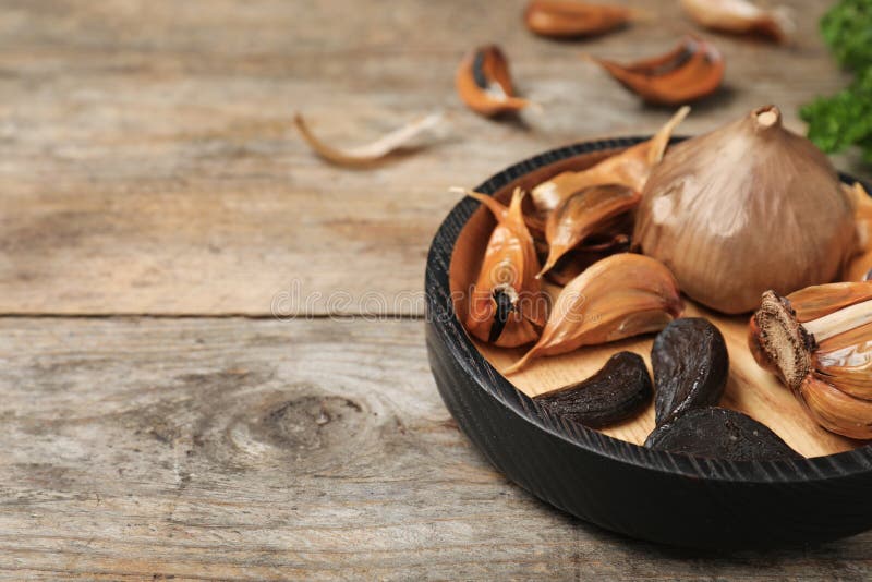 Bowl with black garlic on wooden table