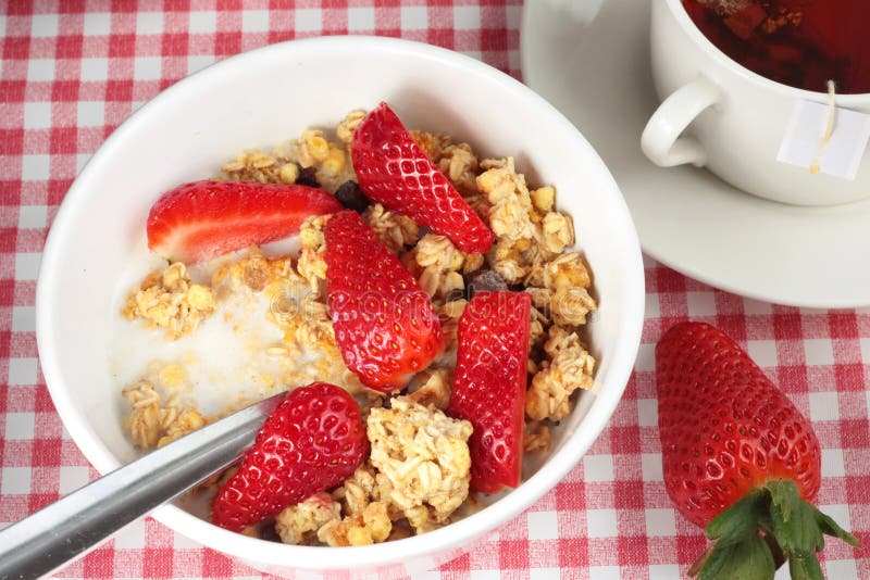 Bowl of cereal with strawberries and a cup of tea