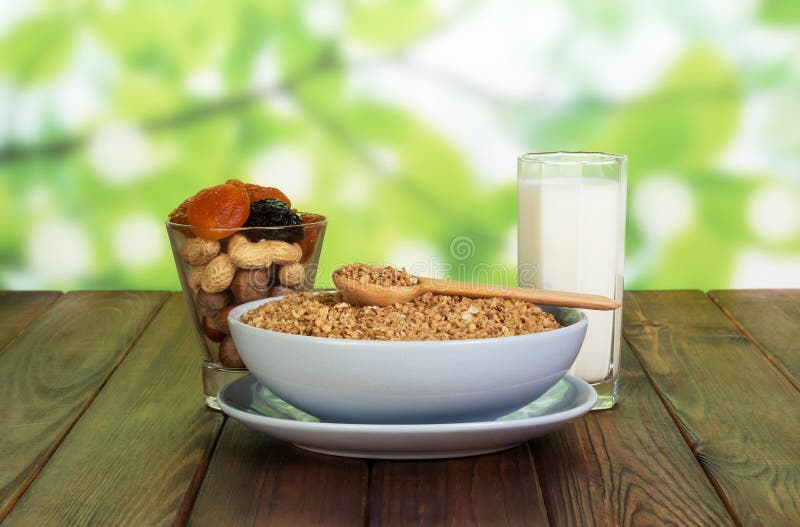 Bowl Cereals, Nuts, Dried Fruit, Glass Milk on Abstract Green. Stock