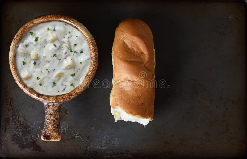 A bowl of Clam Chowder  and a baguette on a baking sheet