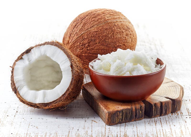 Misku kokosový olej a čerstvé kokosy na biely drevený stôl.