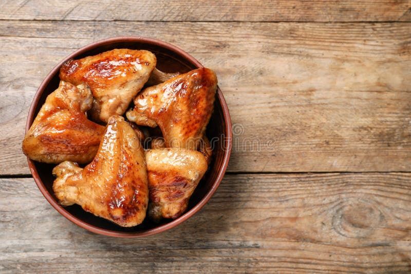 Bowl with Delicious Fried Chicken Wings on Wooden Table, Top View