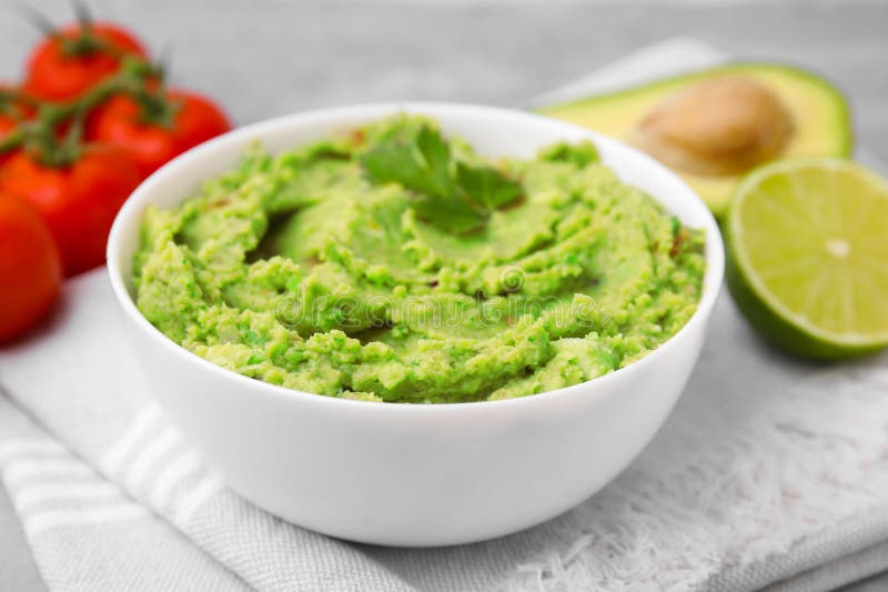 Bowl of delicious guacamole and ingredients on cloth, closeup royalty free stock images