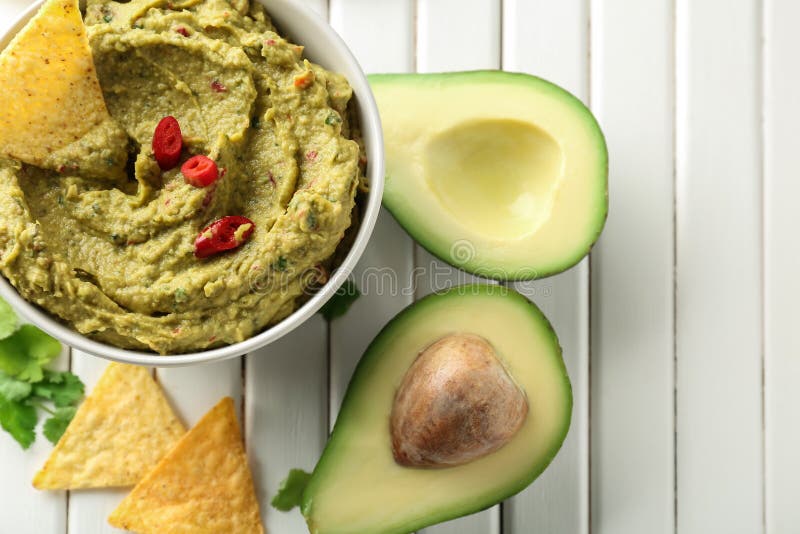 Bowl with delicious guacamole and nachos on wooden table stock photo