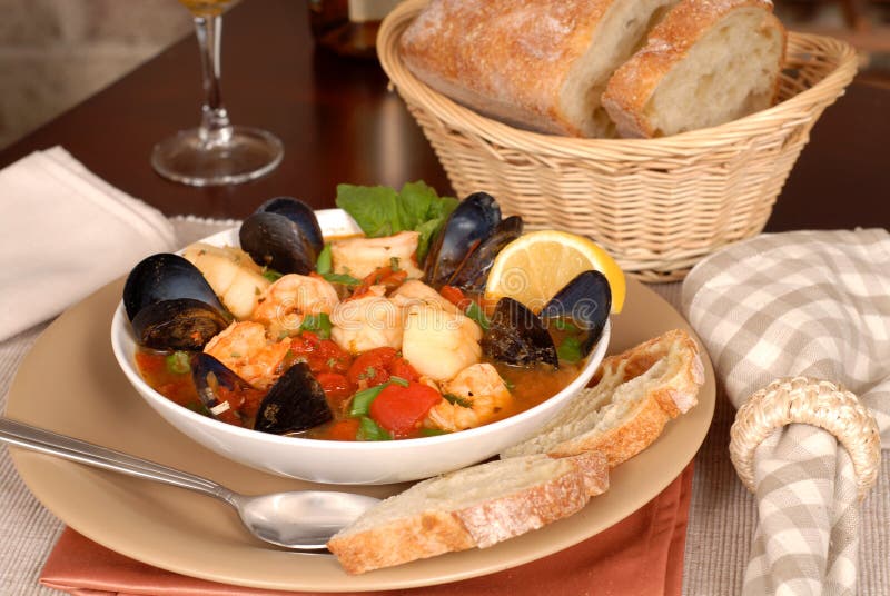 Bowl of delicious seafood soup with wine and rustic bread