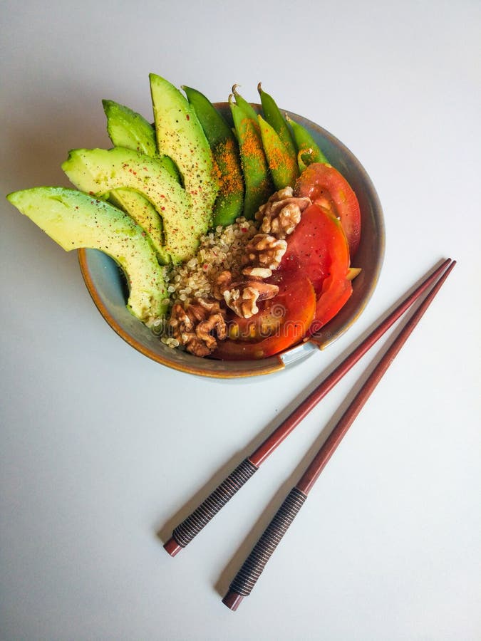 Bowl di cibo reale, cibo naturale, con quinoa, pomodoro, noci e avocado Con fondo bianco e bastoncini cinesi fotografia stock