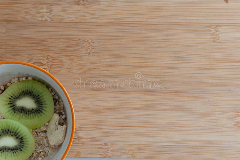 Bowl di muesli con frutta fresca Dall'alto, ciotola di ceramica bianca di muesli con fette di kiwi freschi su tavola di legno immagine stock