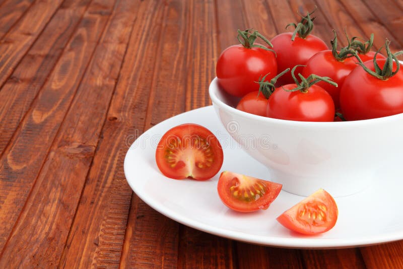 Bowl filled with cherry tomatoes on wooden background