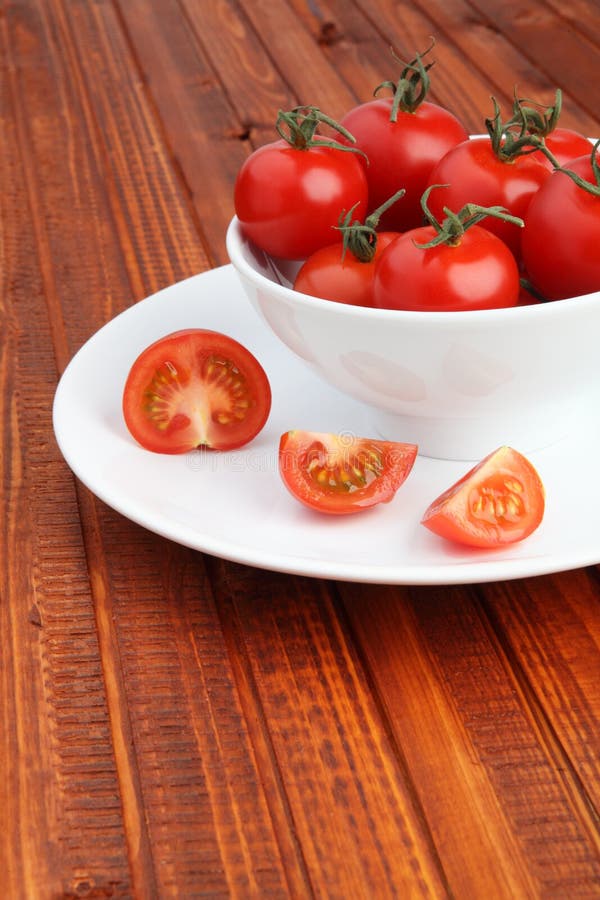 Bowl filled with cherry tomatoes on wooden background