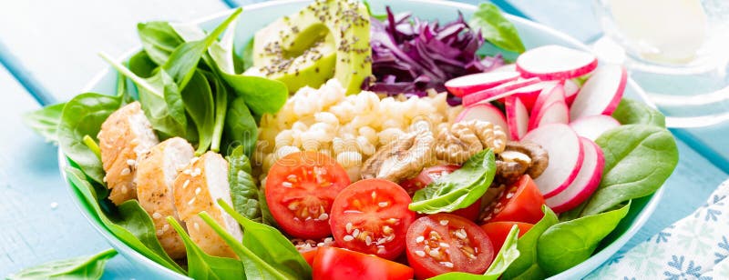 Bowl with grilled chicken meat, bulgur and fresh vegetable salad of radish, tomatoes, avocado, kale and spinach leaves. Healthy a