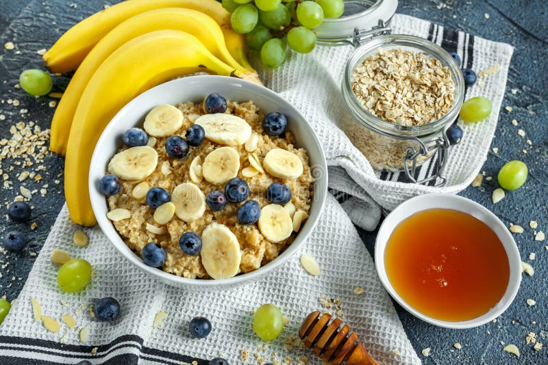 Bowl of Healthy Breakfast oatmeal with ripe blueberries, banana, honey, almonds and green grape. Top view stock photo Bowl of Healthy Breakfast oatmeal with ripe blueberries, banana, honey, almonds and green grape. Top view stock photo
